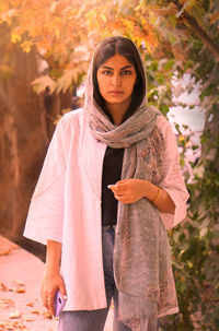 Portrait of young woman standing against trees