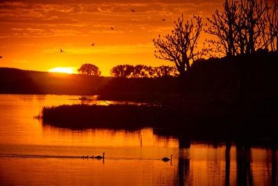 Scenic view of sunset at lake against sky