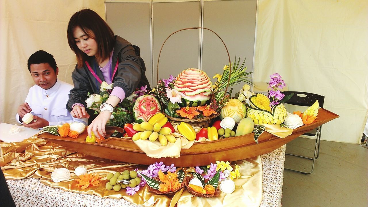 indoors, freshness, food and drink, table, food, lifestyles, leisure activity, flower, casual clothing, holding, standing, person, sitting, variation, bouquet, front view, celebration