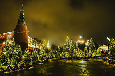 Illuminated building by river against sky at night