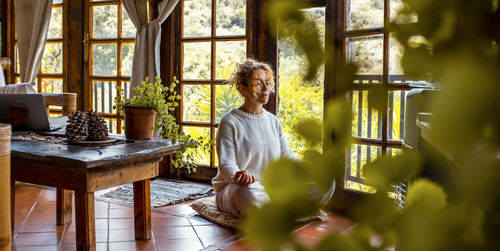 Side view of woman standing by window