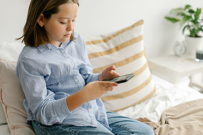 Young woman using mobile phone while sitting on sofa at home