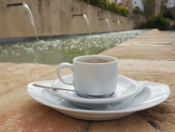 Close-up of empty cup against fountain