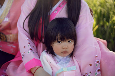 Korean national children pink costume on a four year old girl standing in a field with grass