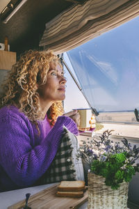 Portrait of young woman using mobile phone while sitting on table