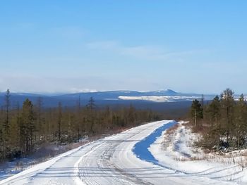 Road amidst snowcapped mountains against sky