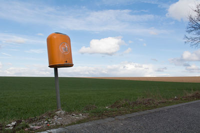 Road sign on field against sky