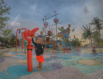 Boy playing with umbrella against sky