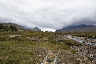 Scenic view of landscape and mountains against cloudy sky