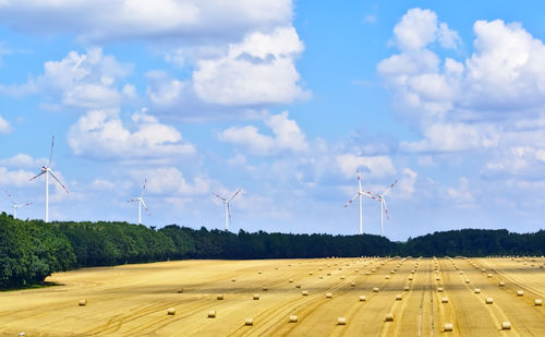 Windmills on field against sky