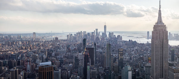 Aerial view of city buildings against cloudy sky