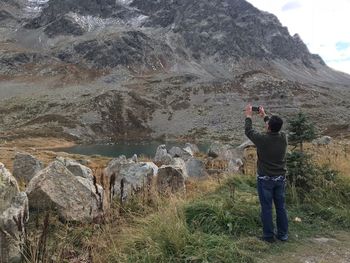 Rear view of man photographing on rock