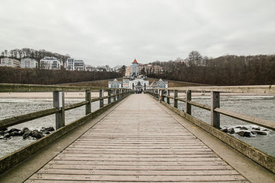 Pier on river against cloudy sky