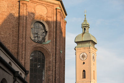 Low angle view of clock tower amidst buildings against sky