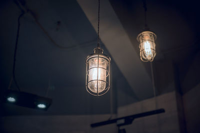 Low angle view of illuminated light bulb hanging from ceiling