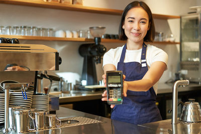 Portrait of young woman using mobile phone at restaurant