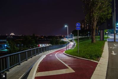 Empty road along illuminated street lights at night