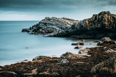 Scenic view of sea by cliff against sky