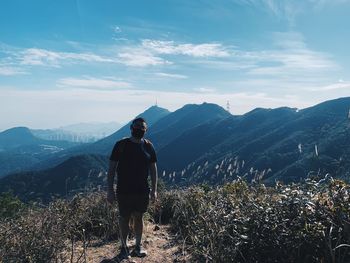 Rear view of man standing on mountain against sky