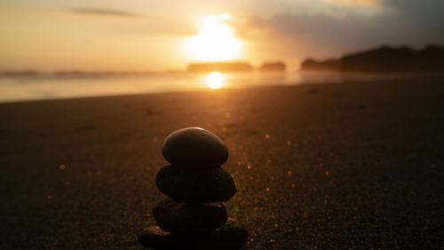 Stack of stones on beach during sunset