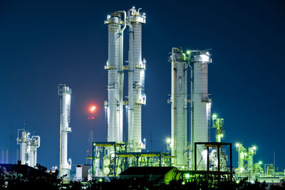 Low angle view of illuminated factory against sky at night