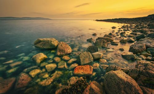 Orange sunset seascape scenery of rocky coast at wild atlantic way in barna, galway, ireland