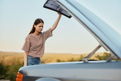 Rear view of young woman standing against car