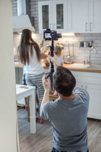 Rear view of woman photographing at home