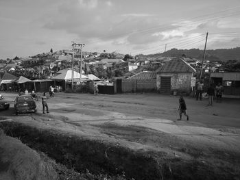 People on houses by buildings in city against sky