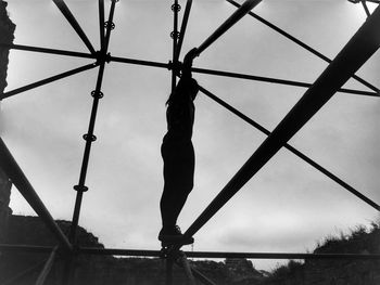 Low angle view of silhouette girl balancing on metallic structure