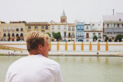 Rear view of man against river in city