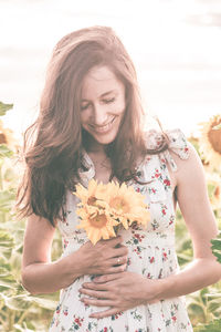 Close-up of a beautiful young woman standing against white flowering plants