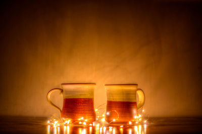 Wine glass on table against illuminated wall