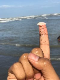 Cropped image of person hand against sea