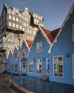 Houses by canal in city against sky