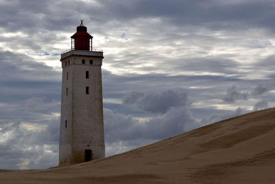 Lighthouse by sea against sky