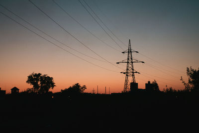 Silhouette electricity pylon against sky during sunset