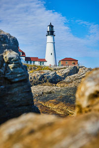 Lighthouse by sea against sky