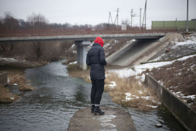 Rear view of person standing in river during winter