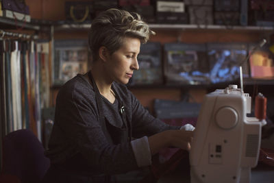 Female fashion designer using sewing machine in studio