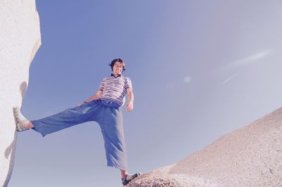 Low angle view of man standing on rocks against clear sky