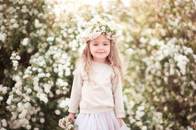 Portrait of girl wearing wreath against flowering plant