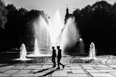 People on fountain in city