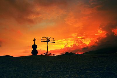 Silhouette guitar and equipment against dramatic sky during sunset