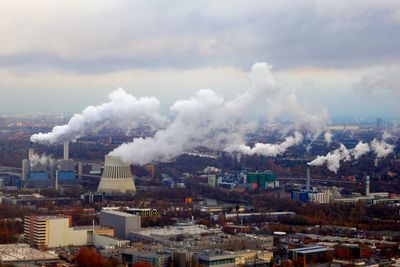 High angle view of smoke emitting from city against sky