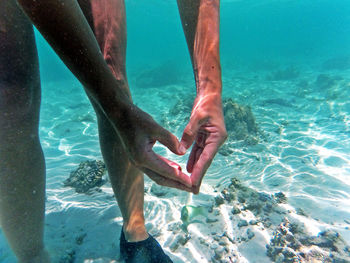 Cropped image of woman making heart shape in sea