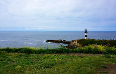 Lighthouse by sea against sky