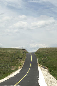 Under the blue sky and white clouds, a flat broad asphalt road leads to the front