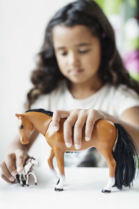 Girl playing with toy horse at table