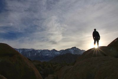 Rear view of man standing on top of mountain at sunset
